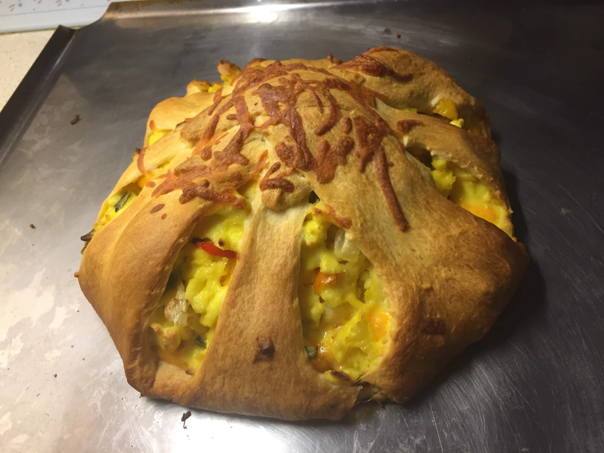 A golden-brown baked dish with a flaky crust and colorful filling peeking through.