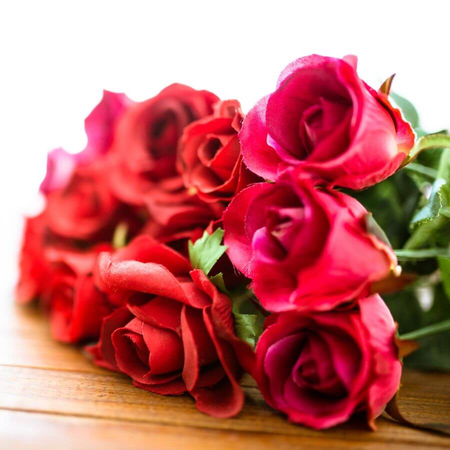 A bouquet of red roses arranged on a wooden surface.